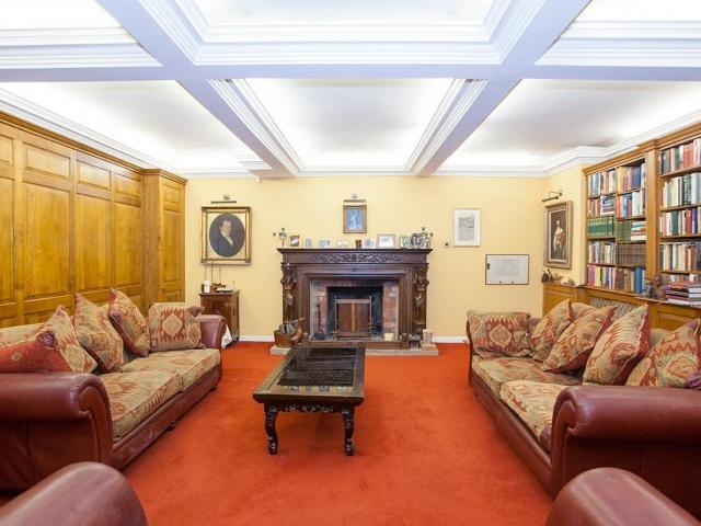 The spacious first reception room has stone mullion windows to the front, a feature window to the side and a fireplace with open fire.