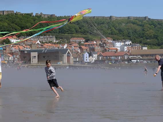 Children fly kites on the beach against Scarborough's iconic backdrop.