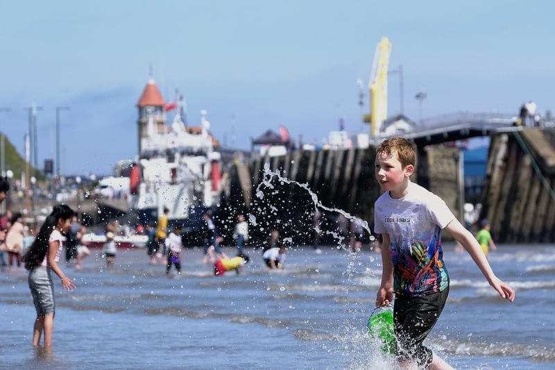 A boy splashes in the sea, bucket in hand