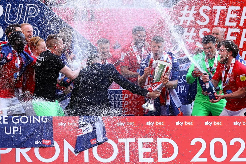 Morecambe spray the champagne after being presented with the League Two play-off final trophy