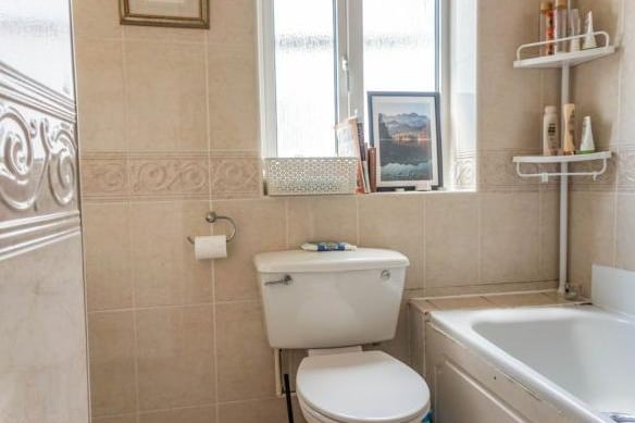 The family bathroom is fully tiled in a simple, neutral colour, with a bath with shower over, wash hand basin, W.C. window to the rear and radiator.