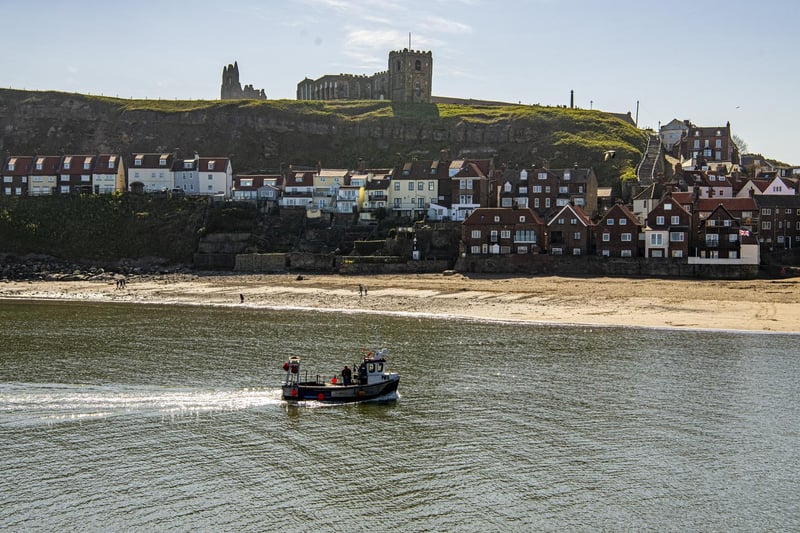 A fishing boat returns back to Whitby harbour in fine weather