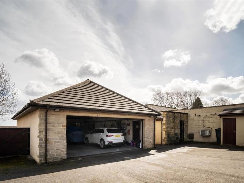An electrically operated gated entrance leads onto an extensive paved forecourt with parking space for several vehicles, and there is a quadruple garage.