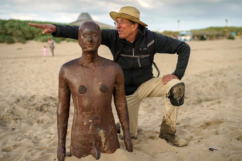 Artist Sir Antony Gormley checks the alignment of one of his statues as he oversees the replacement foundations of his installation 'Another Place' on Crosby Beach