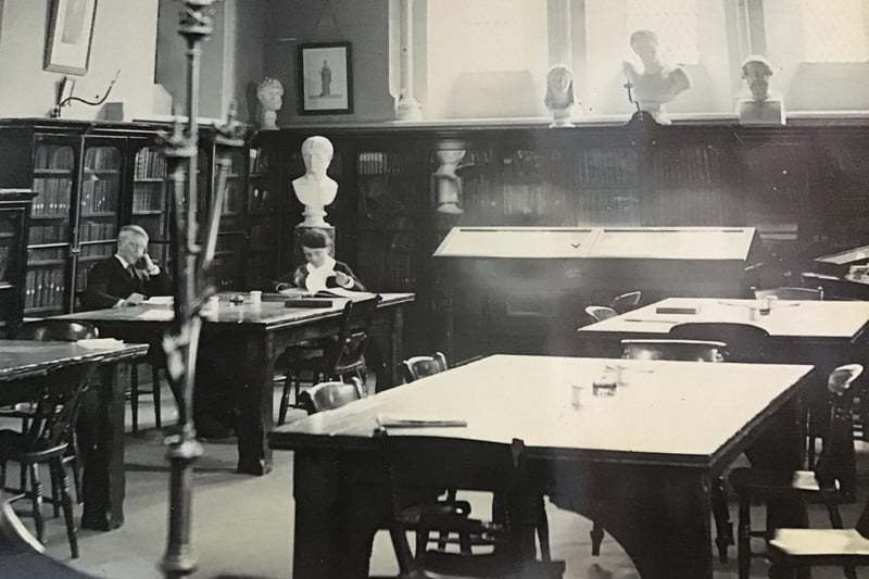 Scholars at their desks which could be either a classroom or a library
