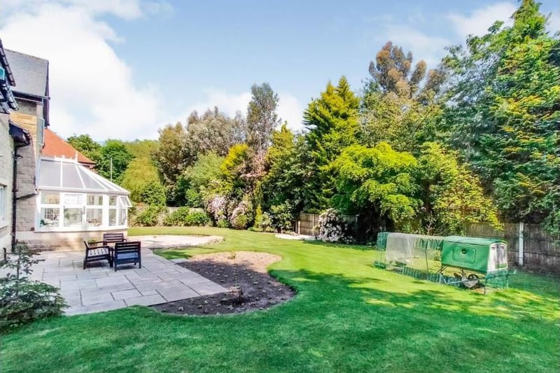 The rear garden is enclosed and features an extensive lawn bordered by established trees providing privacy and attractive flower beds.