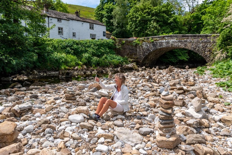 Jane Gill, aged 62, of Barnard Castle in County Durham, walks along the dry riverbed of the River Wharfe close to the George Inn at Hubberholme, North Yorkshire.