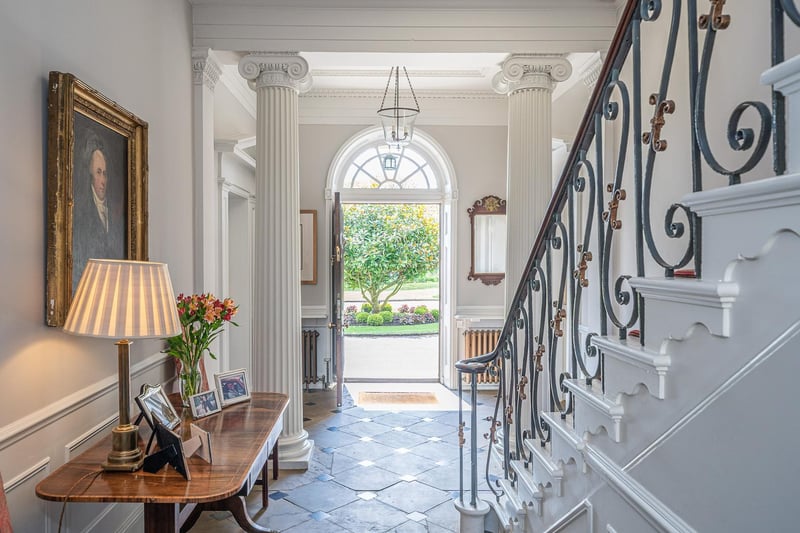 A staircase with wrought iron balustrade leads up from the hallway
