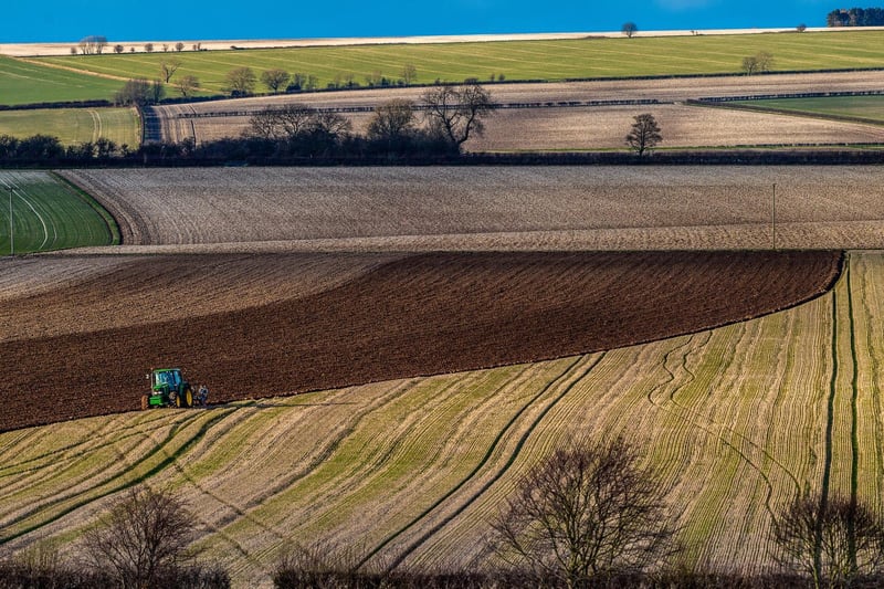 A farmer slowly ploughs a field during the early evening sun on The Wolds near Huggate, East Yorkshire.