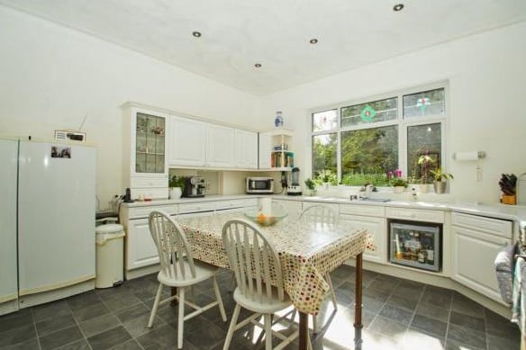 The modern kitchen is decorated in whites and greys, with fitted appliances and a window with views overlooking the garden. There is also a utility room on this floor