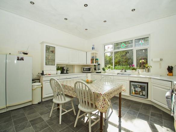 The modern kitchen is decorated in whites and greys, with fitted appliances and a window with views overlooking the garden. There is also a utility room on this floor