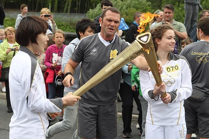 The Olympic Torch is passed onto it's next recipient.