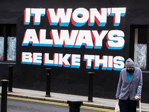 A man walks past a mural by Emmalene Blake in Dublin's city centre quoting a song title by Irish rock band 'Inhaler'