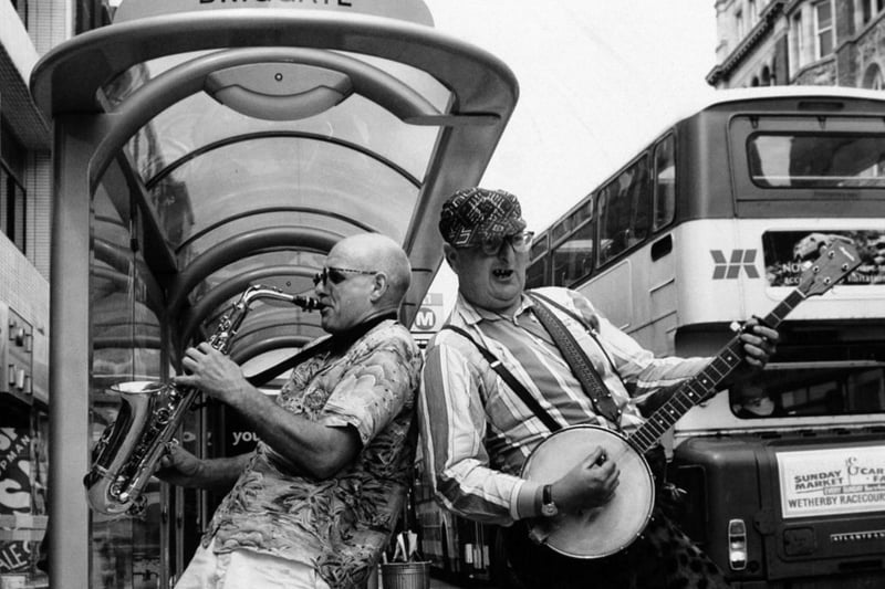 Buskers Moon de Lune take their two-man act on a bus-stop tour of Leeds in July 1993, part of a 50-mile trip to nine different town centres, as a prelude to the city's Centenary Wind Festival.