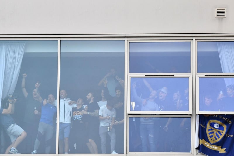 Leeds United players at a window inside the stadium gesture to supporters gathering outside Elland Road.