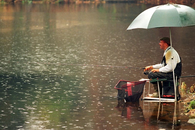 An angler waits patiently for a catch in the pouring rain alongside the River Aire at Wetherby in November 1995.