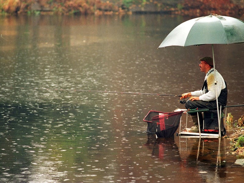 An angler waits patiently for a catch in the pouring rain alongside the River Aire in November 1995.