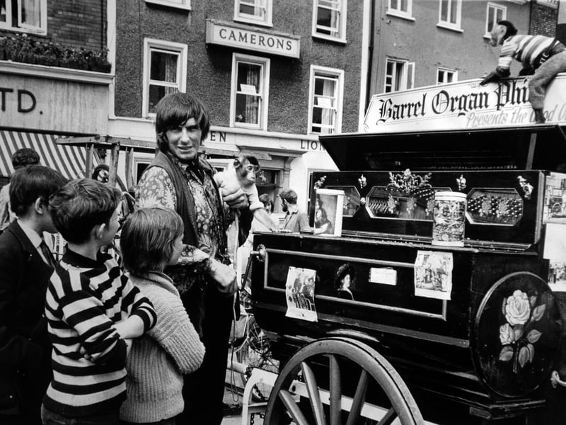 Young boys surround Phil, the barrel-rogan man, who is performing in St. Sampson’s Square with his monkeys on July 22, 1971.