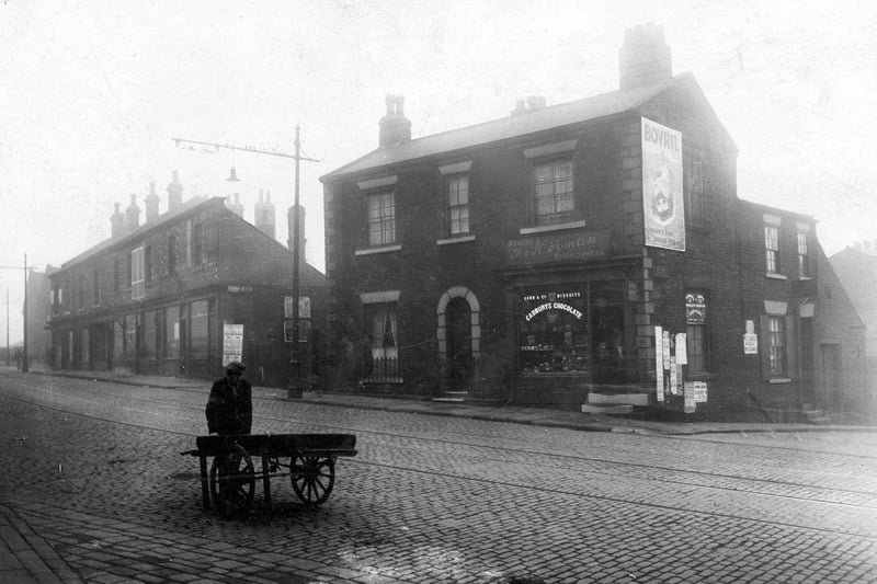 Burley Road in October 1928 featuring the premises of F and H Tomlin, confectioners. On the left is a row of shops, and to the right, the junction with St. Andrews Street.
