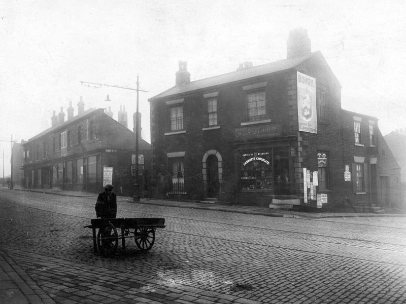 Burley Road in October 1928 featuring the premises of F and H Tomlin, confectioners. On the left is a row of shops, and to the right, the junction with St. Andrews Street.