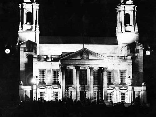 A view of Leeds Civic Hall taken around 10.45pm on the evening of the VJ celebrations. People can be seen silhouetted against the white portland stone floodlit building.