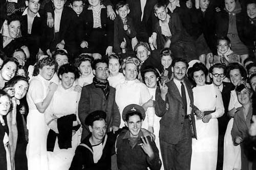 This photograph was taken at 1.30am, when celebrations continued into the early hours. The group includes nurses, servicemen and children.