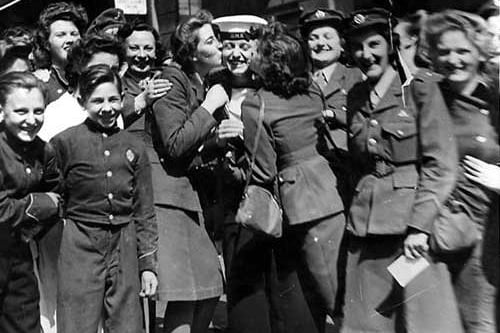 Outside the NAAFI Club on Albion Street, scene of jubilation on VJ Day. The sailor in the middle is being kissed by two WAAFS.