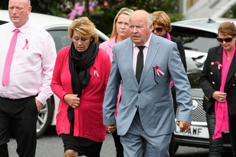 Mourners dressed in pink follow behind the funeral cortege.