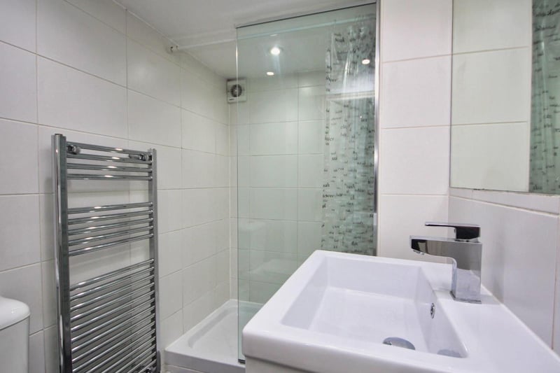 The bathroom is fully tiled in white ceramics, grey tiled floor, shower cubicle with glass screen and mixer shower, WC and wash hand basin.