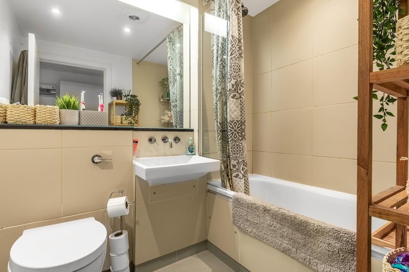 The light and modern bathroom is a three piece suite with over bath shower and full height wall tiling. It has a neutral decor, making it easy for a new owner to add their own touches, and also benefits from a large illuminated mirror.