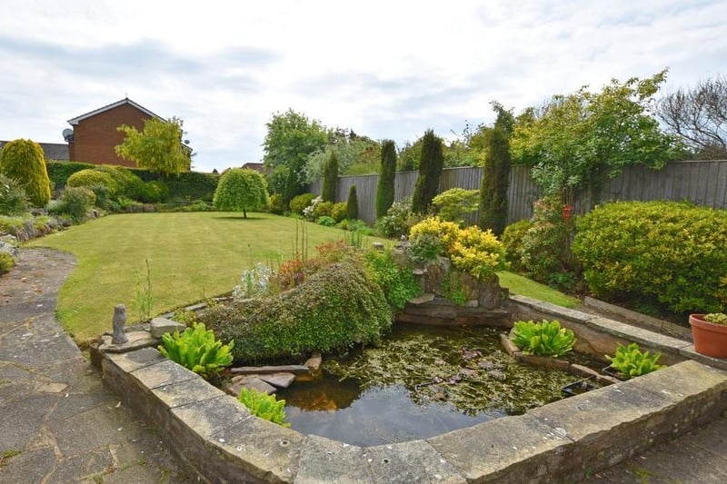 A lawn and well established borders form the rear garden, with its feature pond.