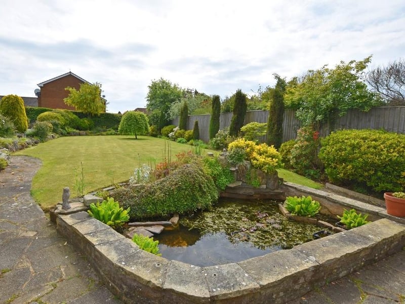 A lawn and well established borders form the rear garden, with its feature pond.