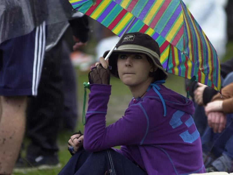 A reveller takes shelter from the rain on day two of Leeds Festival in August 2000.