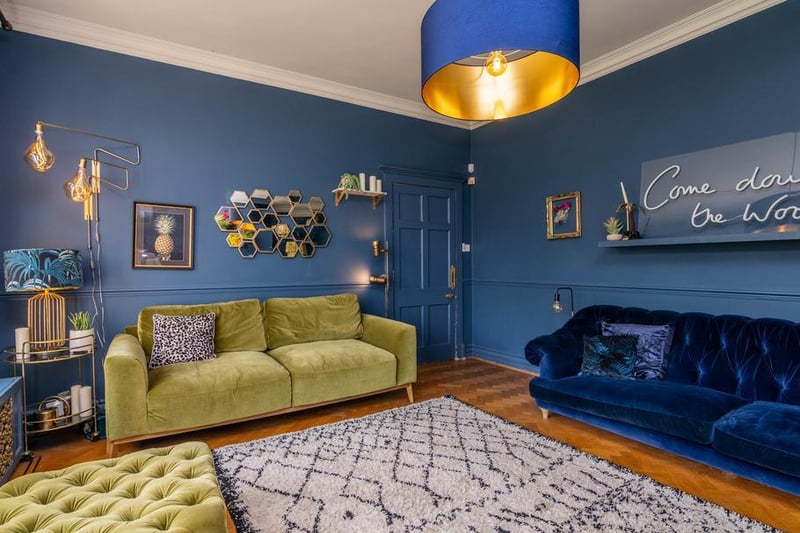 From the hallway is the main living room, complete with neon Come Down to the Woods sign, a nod to the family name and the Instagram handle. This room combines bright blues with olive greens, rich velvet textures and the traditional wood  burning stove to create a warm and inviting space for the whole family.