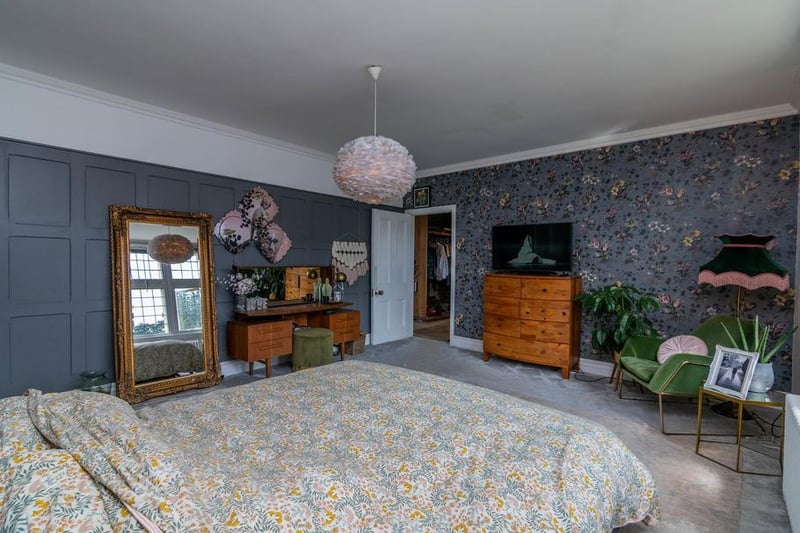 The upper floors of the home have six bedrooms and three bathrooms. This room is a mix of grey panelled walls, a feature flowered wallpaper and arch panels painted on the back wall, creating a unique feature behind the bed. It also benefits from a beautiful en suite and walk-in dressing room.