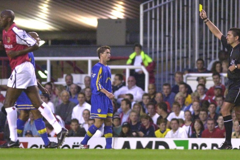 Referee Jeff Winters hands out a yellow card to Olivier Dacourt as team mate Harry Kewell looks on.