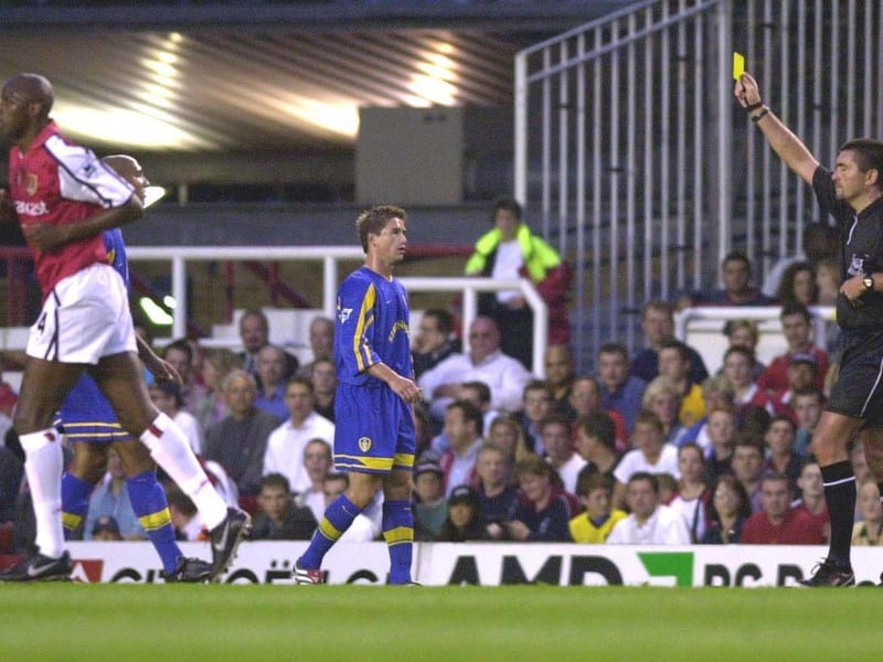 Referee Jeff Winters hands out a yellow card to Olivier Dacourt as team mate Harry Kewell looks on.