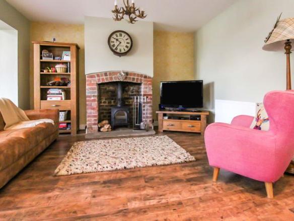 The living space is perfect for family life. Centred around the log burning fire, there's plenty of space for sitting and relaxing. The current owners have added a pop of colour with an eye-catching pink chair.