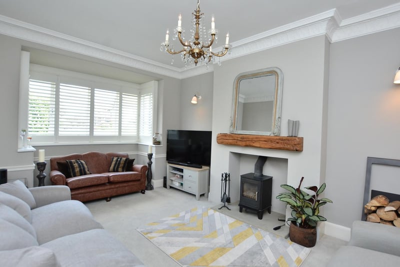Accessed from the hall is the living room, a cosy family space with a deep rectangular bay window to the front elevation with plantation shutters and a multi-fuel burning stove with oak beam mantlepiece.