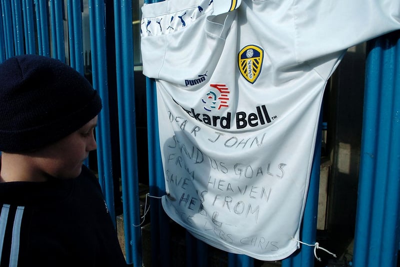 A young fan reads a message left on a Leeds United shirt in memory of former player John Charles.