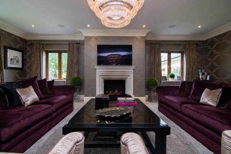 The formal living room is a luxurious yet inviting room, decorated in deep purples and champagne hues. The crystal chandelier and velvet textures add even more depth to this tasteful entertaining space.
