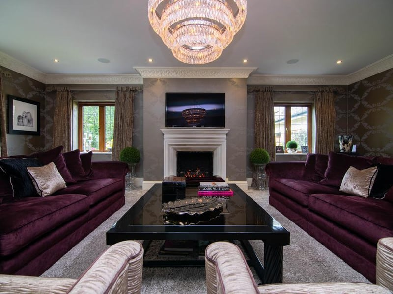 The formal living room is a luxurious yet inviting room, decorated in deep purples and champagne hues. The crystal chandelier and velvet textures add even more depth to this tasteful entertaining space.