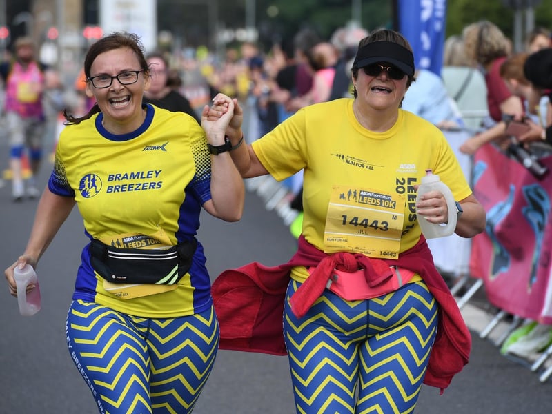 Two runners hold hands as they cross the finish line together.