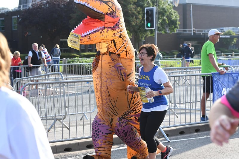 A dinosaur competes alongside human runners