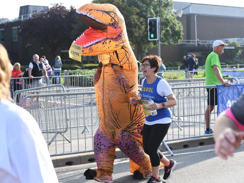 A dinosaur competes alongside human runners