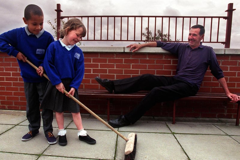 Retiring caretaker Ken Lister watches two of the pupils at Kirkstall Valley Primary School - Steven Bradshaw and Helen Carr - as they get to work with his brush.