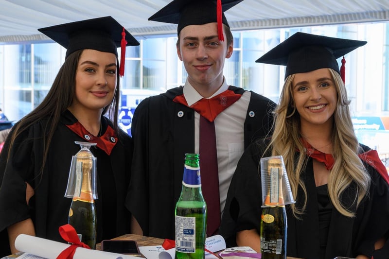 Graduates Lydia Griffin, Tom Harris and Maisie Kewin celebrate under the marquee.