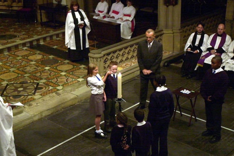 Children from St Peter's C of E Primary School in Leeds light a candle during the service a remember the victims.