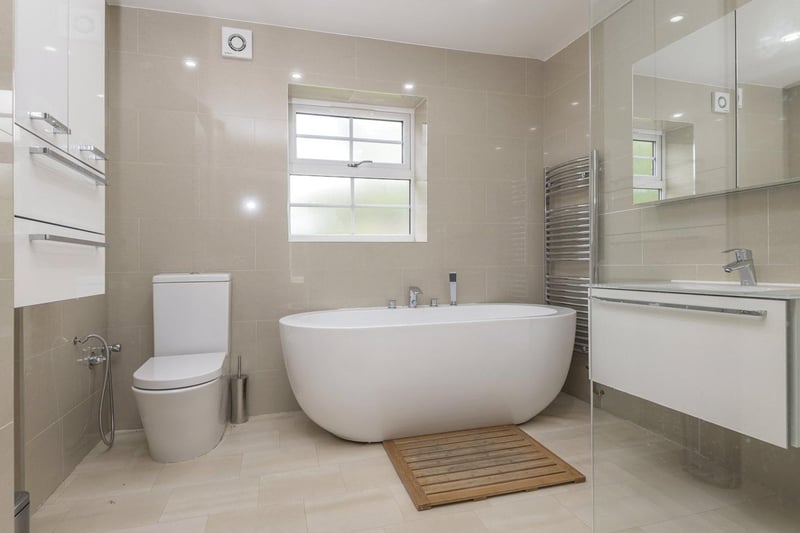 This luxurious bathroom has a deep bath with central taps, located beneath a window.