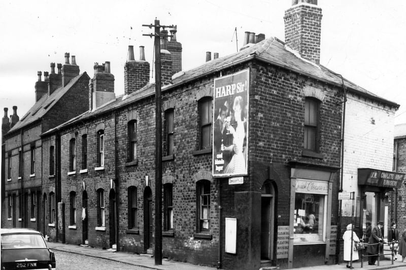 Long view off red brick housing in Dewsbury Place scheduled for demolition in May 1964. The two shops seen are Quick Cleaners (left) and J.M. Stores 'Complete Home Funishers'.